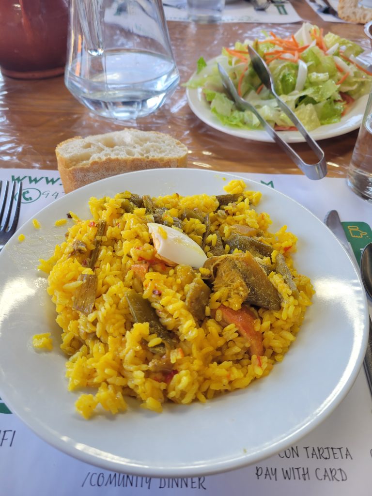 Paella, salad, bread, wine, water, and dessert.